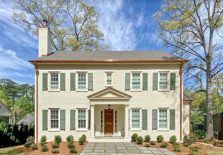 Beautiful painted brick house with green shutters and classic design.