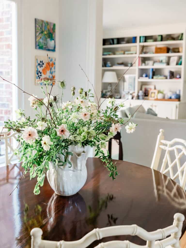 Beautiful flower arrangement in a white vase on a wooden dining table.