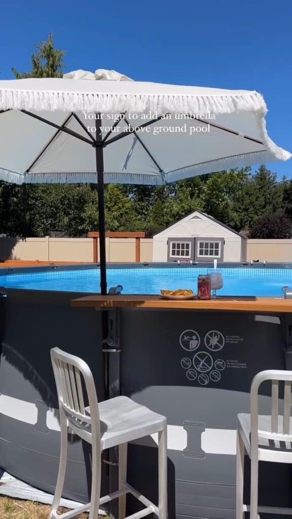 Outdoor pool area with umbrella, hot tub, and backyard in sunny weather.