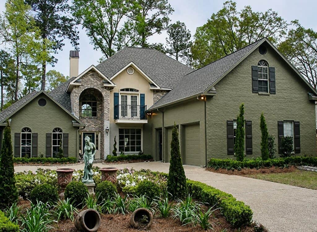 Beautiful painted brick house with lush landscaping and garden statues.