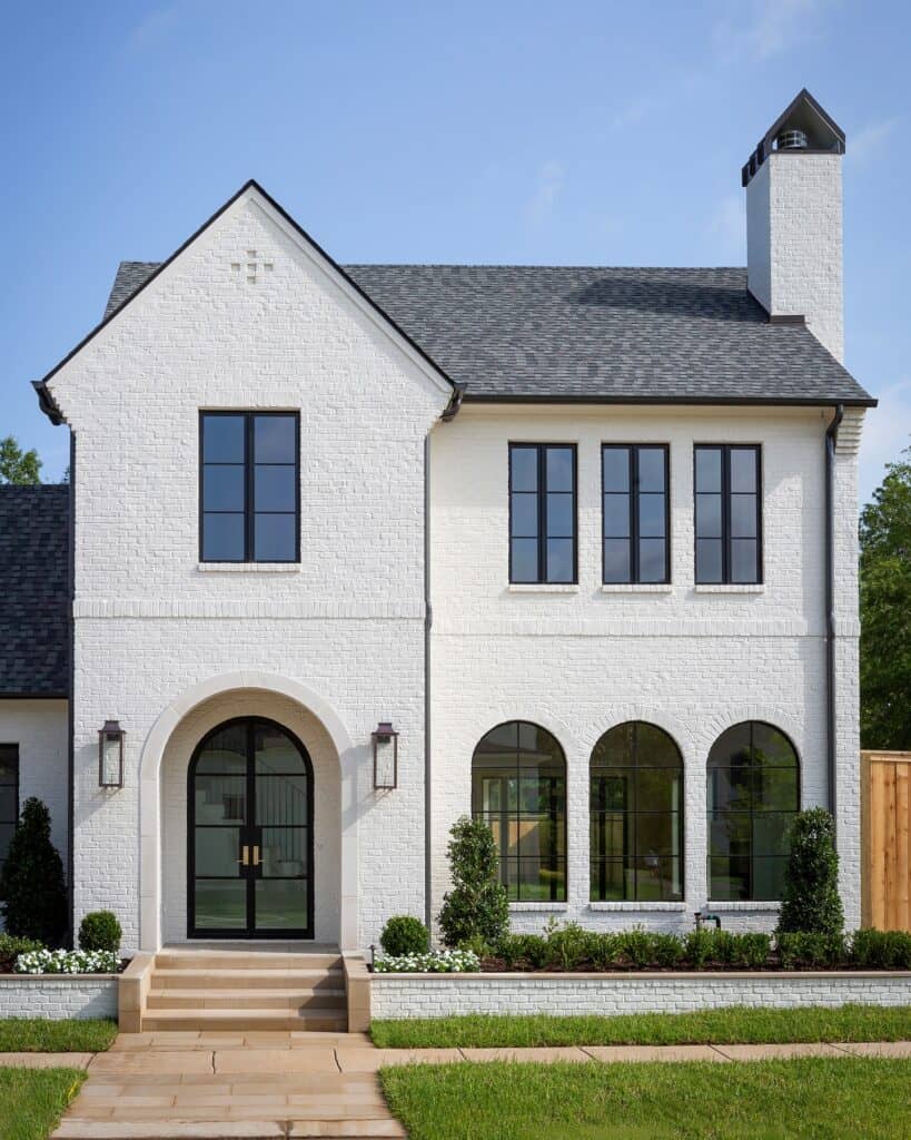 Elegant white brick house with arched windows and black accents.