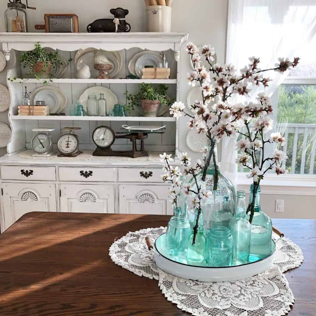 Elegant glass vases with cherry blossom branches on a wooden table with a white lace doily.