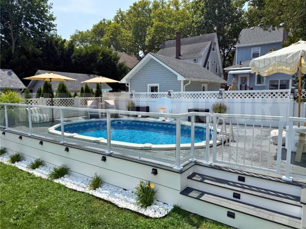 Pool with safety fence, backyard, and neighboring houses in a suburban setting.