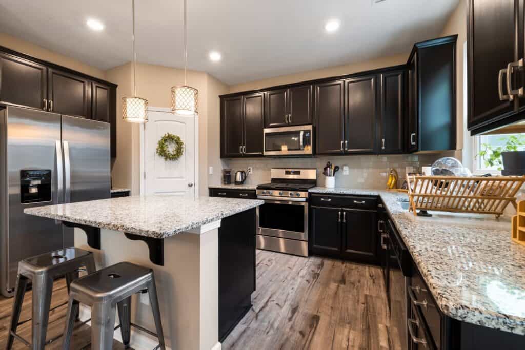 Contemporary kitchen with dark cabinets, granite countertops, and stainless steel appliances.