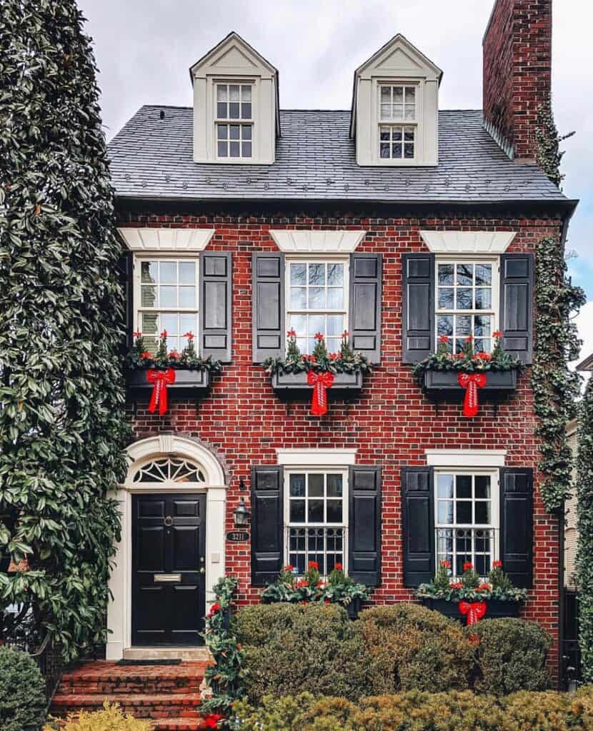 Charming red brick house with black shutters and holiday decorations.