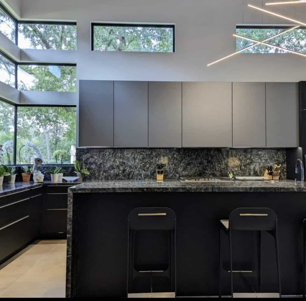 Contemporary kitchen with black cabinets, granite countertops, and large windows.