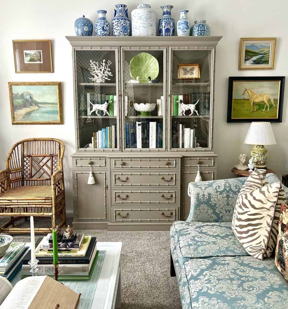 Decorative hutch with blue and white vases, artwork, and cozy living room setting.