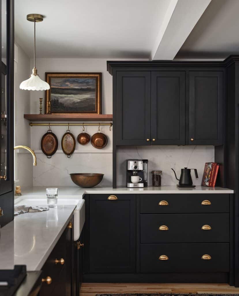 Modern black kitchen cabinets with gold hardware and white marble countertop.