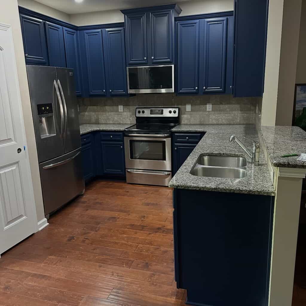 Kitchen with navy blue cabinets, stainless steel appliances, granite countertops.