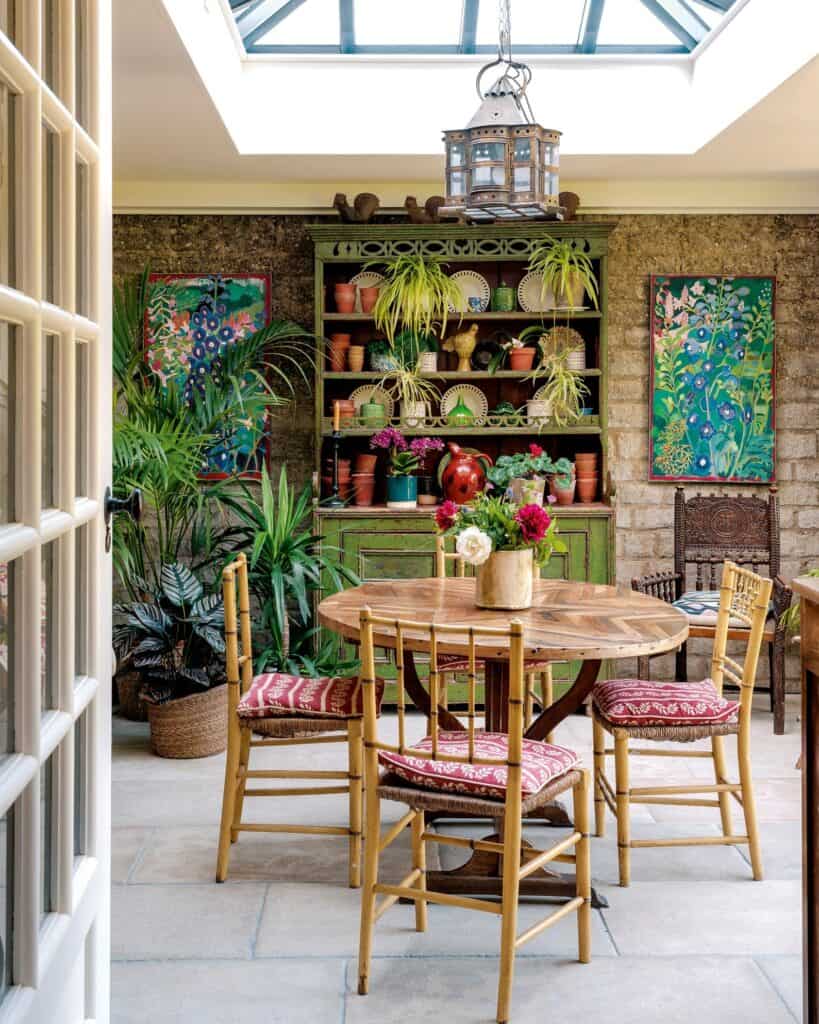 Indoor dining space with wooden table, chairs, and lush green plants.