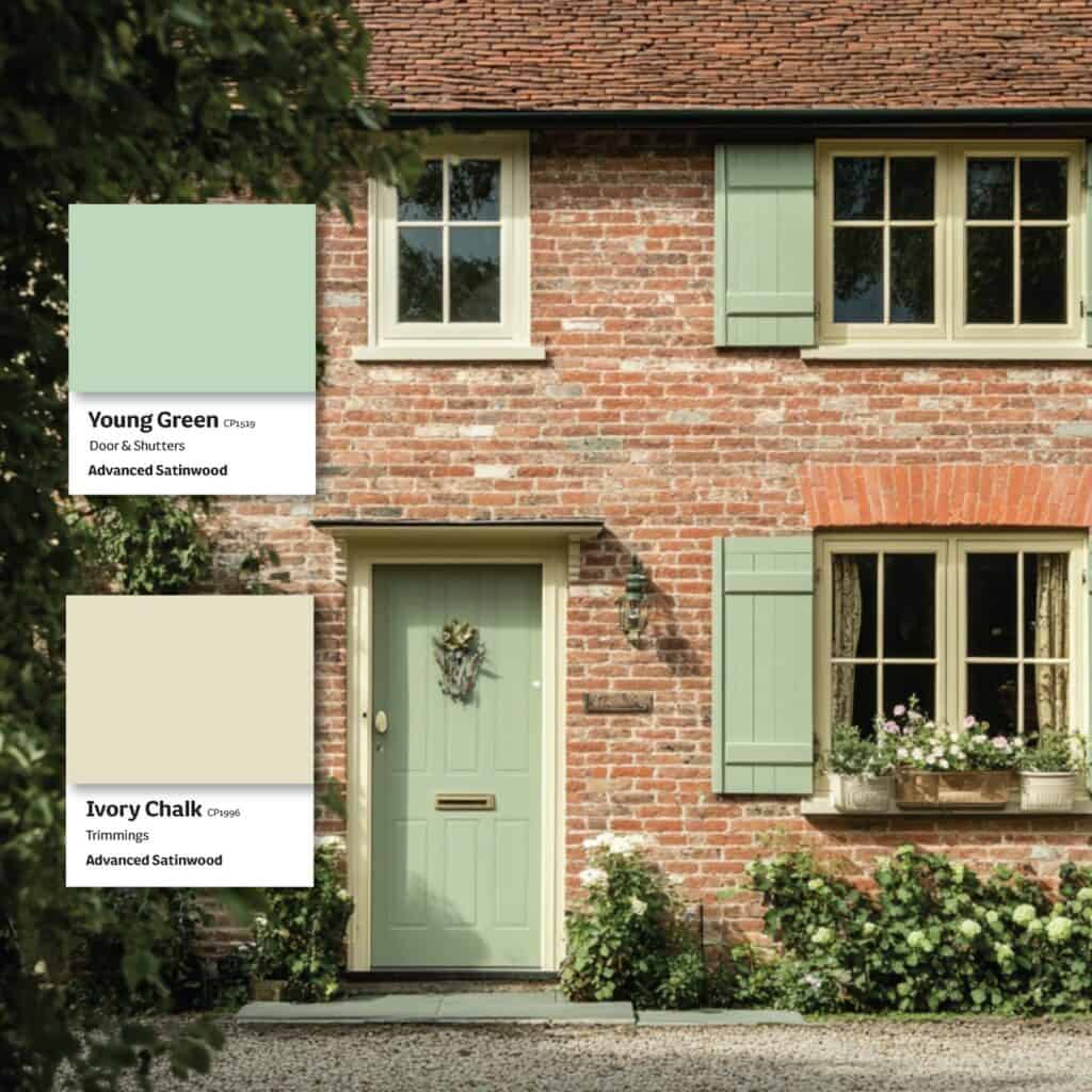 Exterior of a brick house with green and ivory chalk shutters and door.