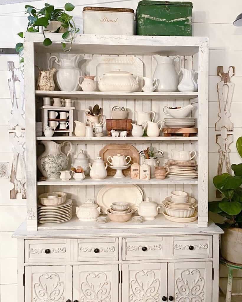 Elegant white hutch with vintage dishes and decor for kitchen styling.