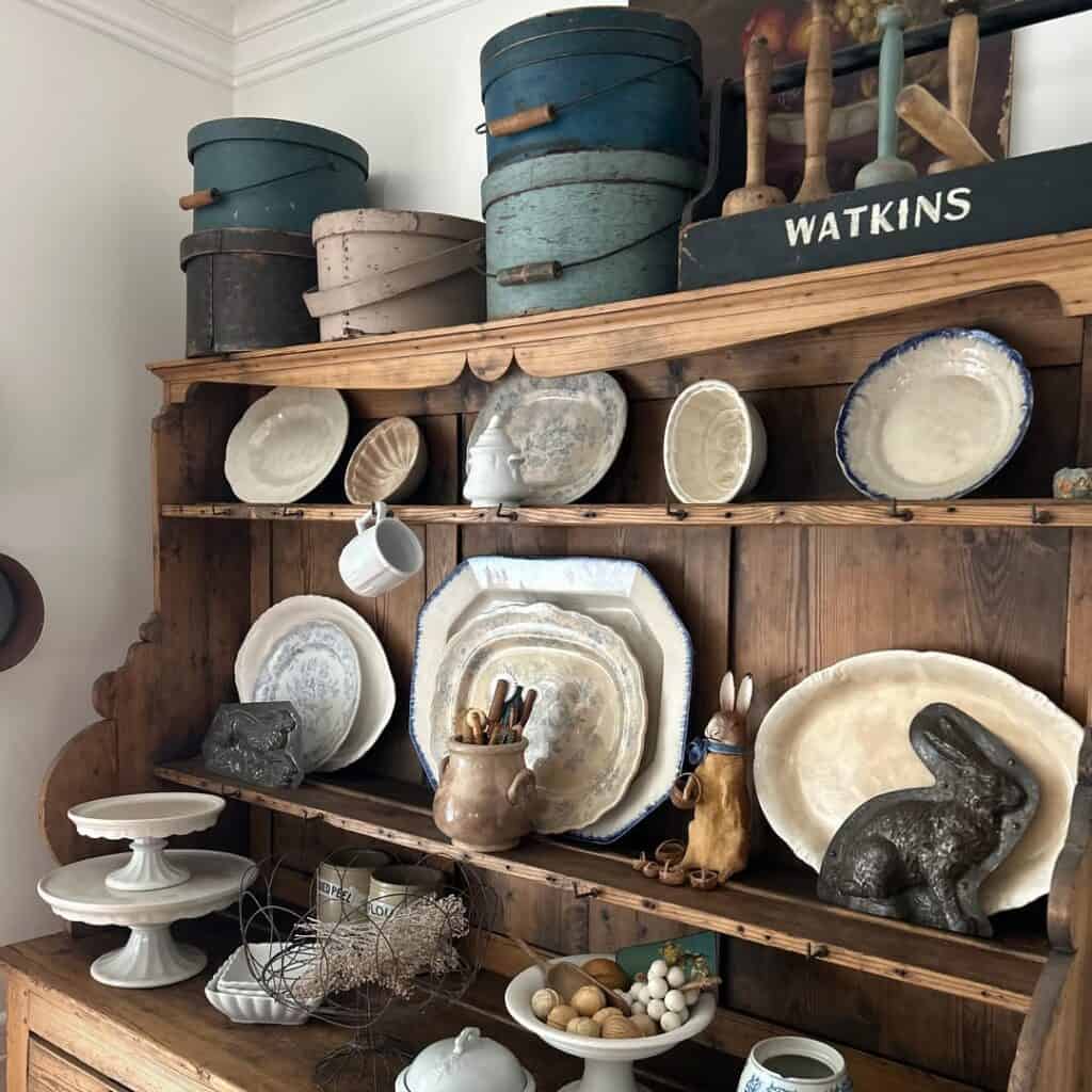 Vintage dishes and decorative items on a rustic wooden hutch for farmhouse style decor.