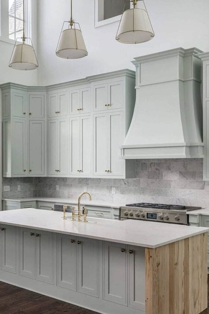 Bright kitchen with light green cabinets and white marble countertops.