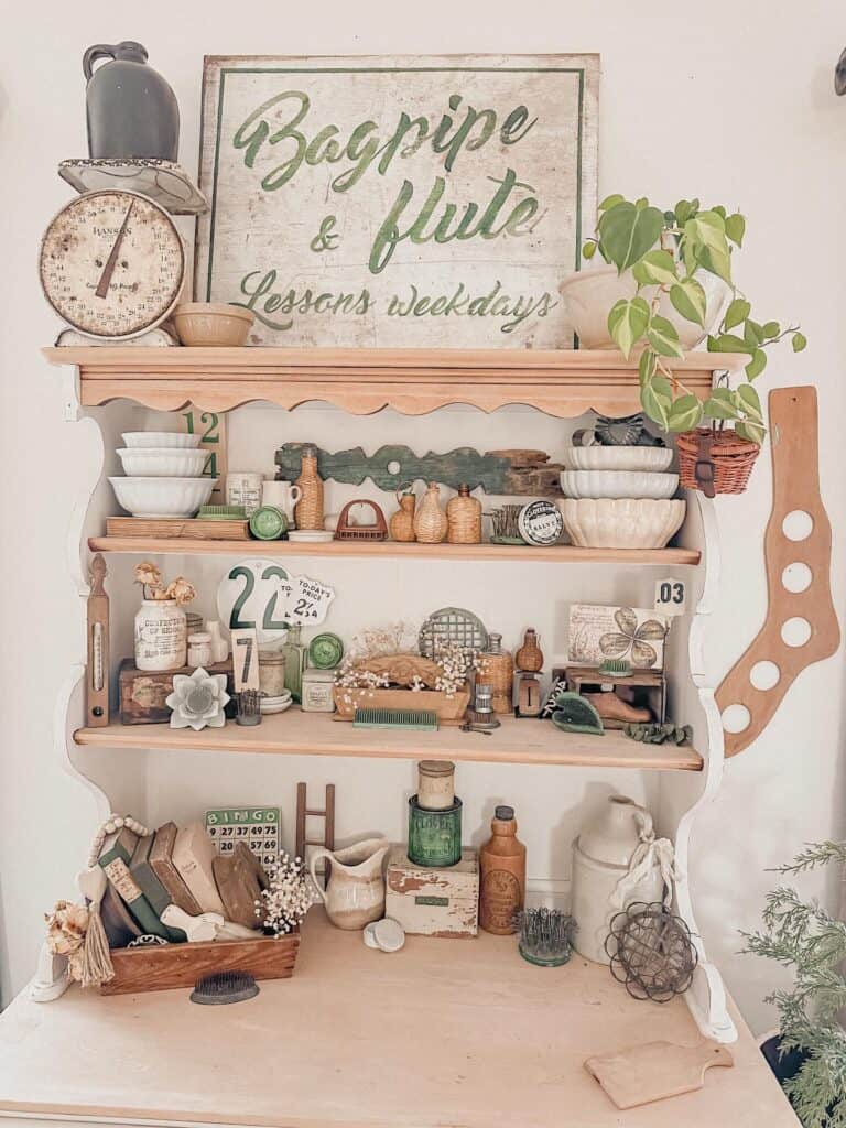Charming hutch decorated with vintage collectibles, plants, and a sign for flute lessons.