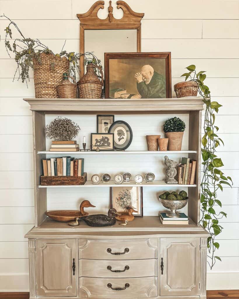 Decorative vintage hutch with plants, books, and art for home styling.
