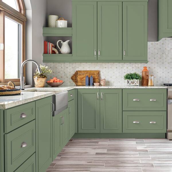Modern kitchen with green cabinets, white countertops, and stainless steel appliances.