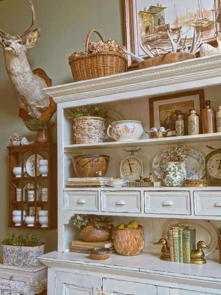 Decorative vintage hutch with baskets, plants, and antique accessories.