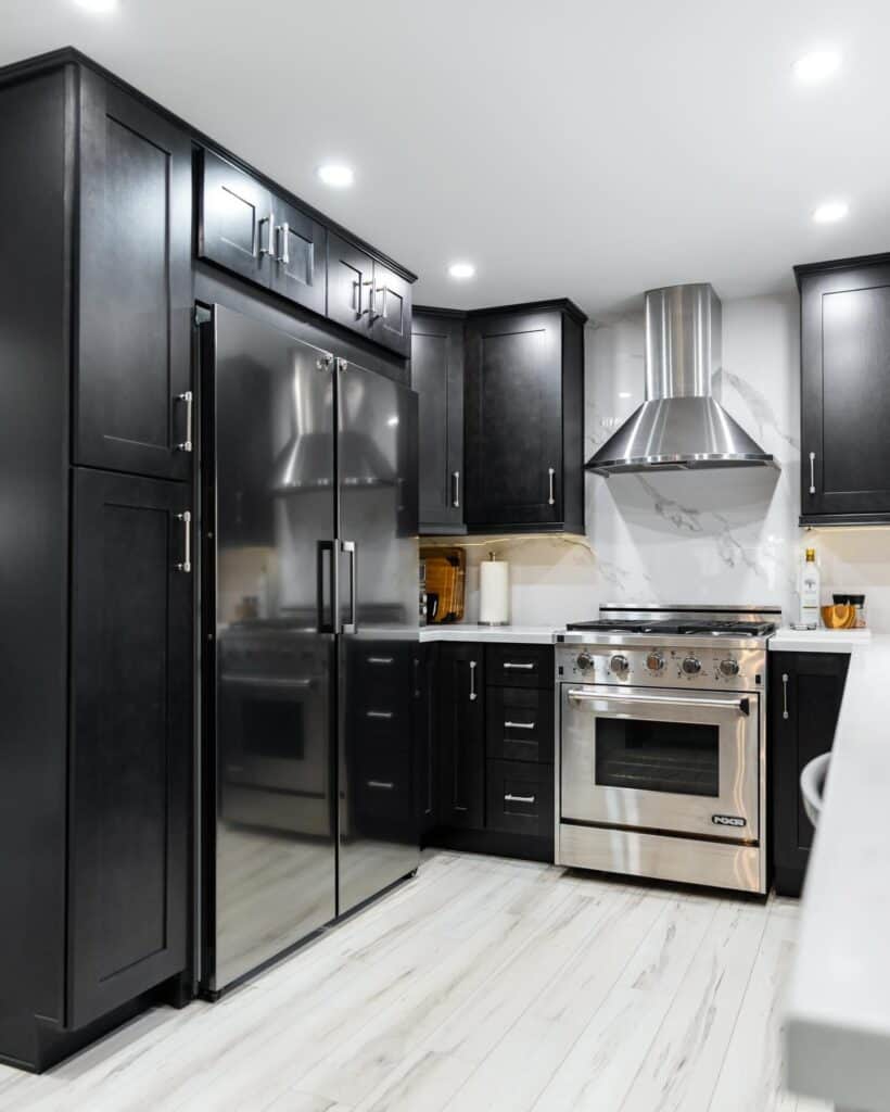 Contemporary black kitchen cabinets with stainless steel appliances and range hood.