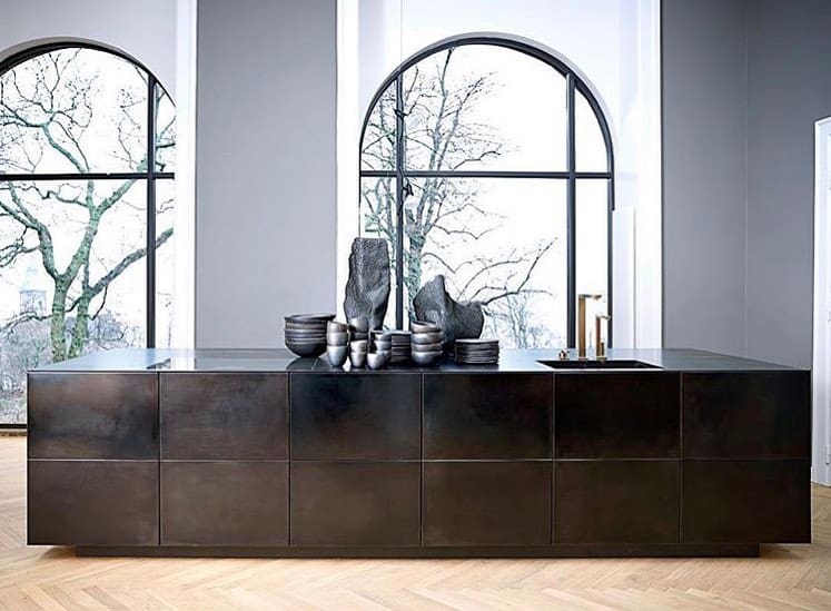 Sleek black kitchen cabinets with large arched windows and decorative vases.