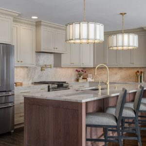 Bright kitchen with white cabinets, marble countertops, and a wooden island.