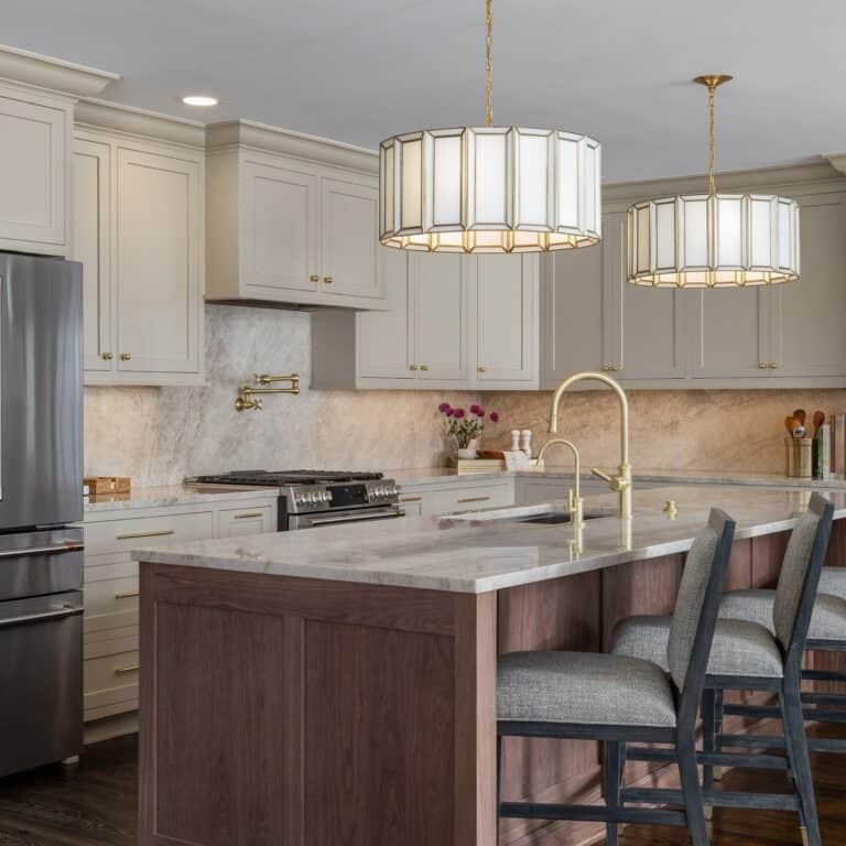 Bright kitchen with white cabinets, marble countertops, and a wooden island.