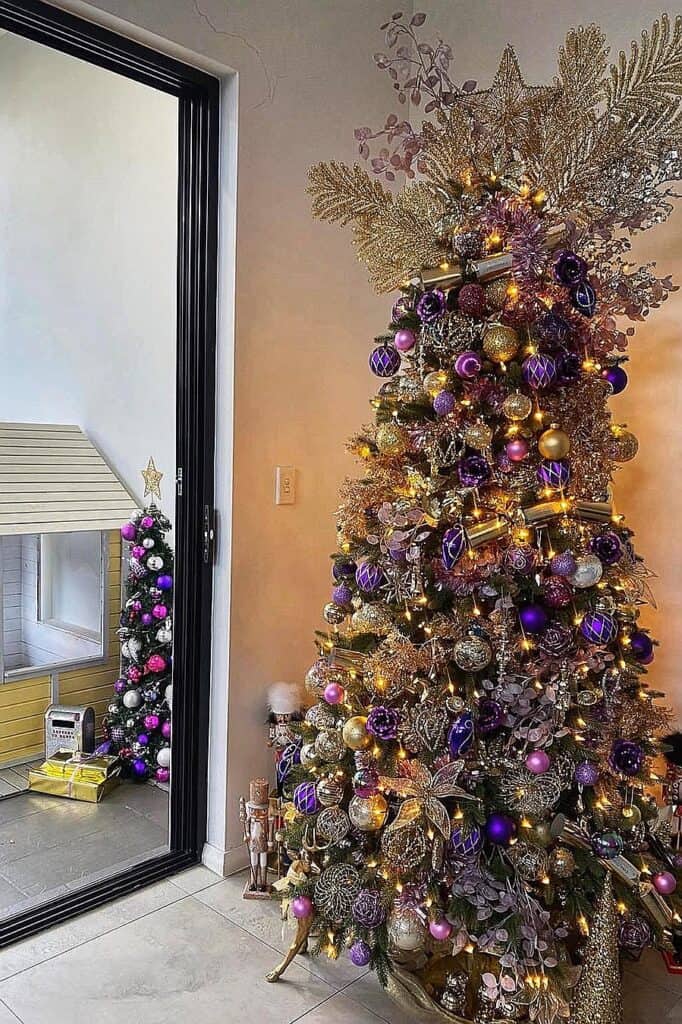Elegant purple and gold Christmas tree with ornaments and lights.