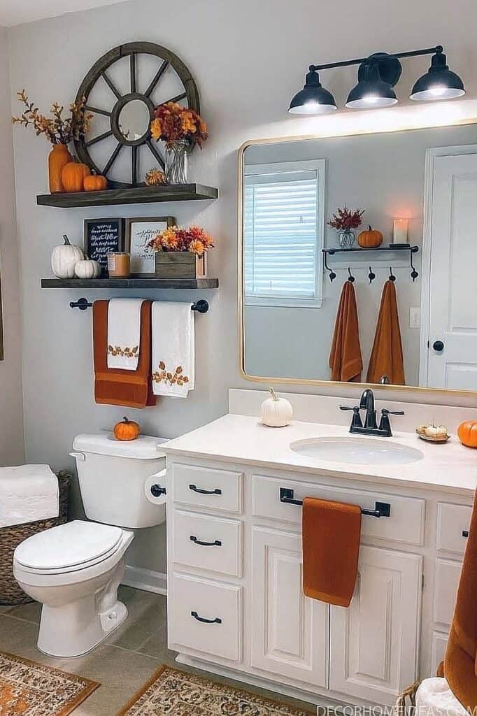 Autumn-themed bathroom with pumpkins, orange towels, and fall decor elements.