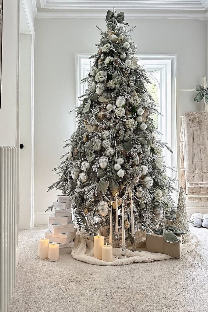 Beautiful white Christmas tree with ornaments, candles, and presents in a cozy room.