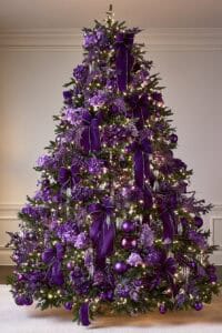 Elegant purple Christmas tree decorated with ribbons, ornaments, and lights.