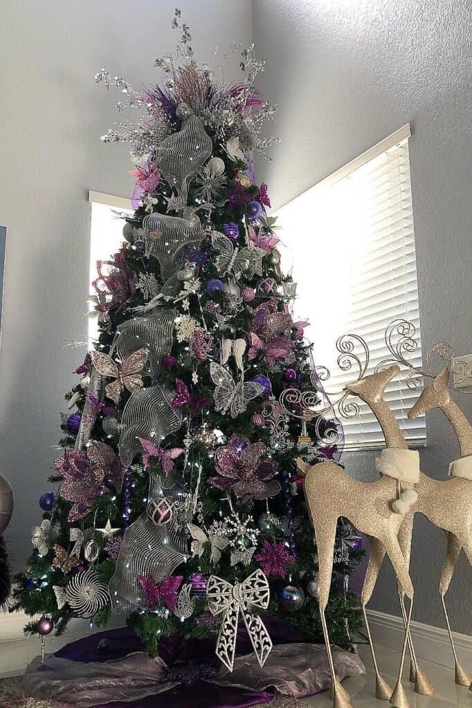 Elegant purple Christmas tree with silver and white ornaments and reindeer figures.