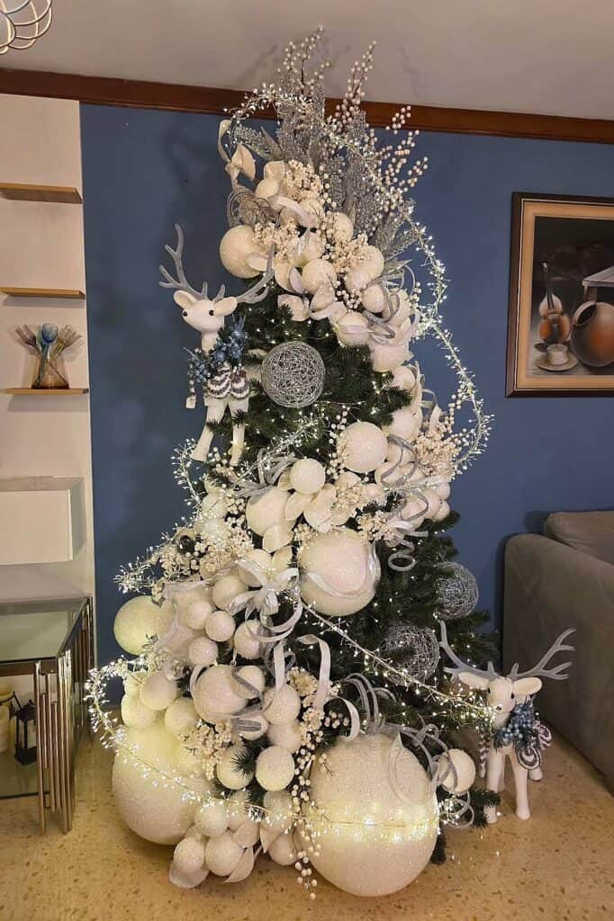 Beautiful white Christmas tree with ornaments, reindeer, and lights for holiday decor.