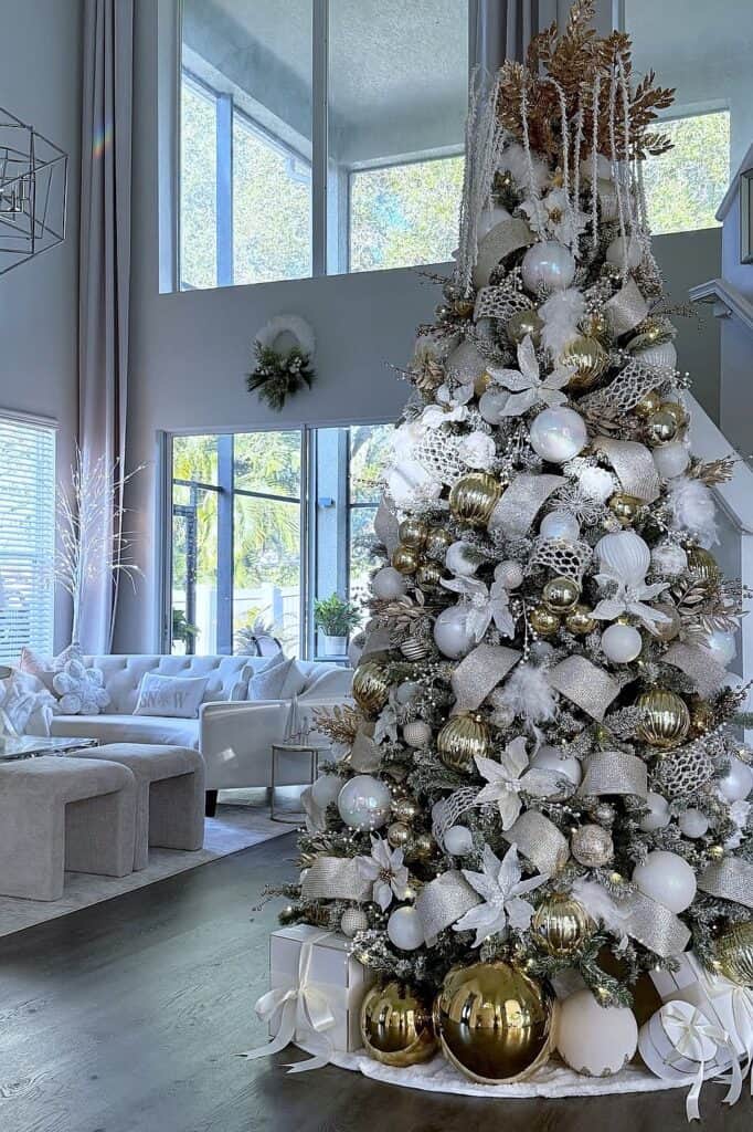 Beautiful white Christmas tree with gold and silver ornaments in a modern living room.