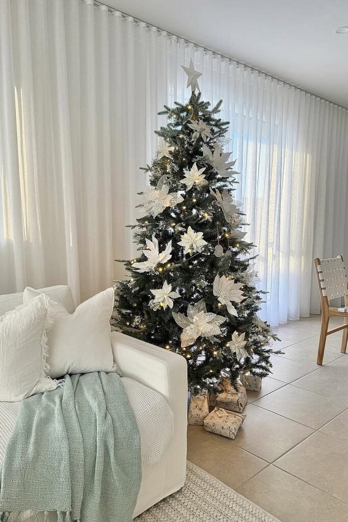 Beautiful white Christmas tree with ornaments and gifts in a modern living room.