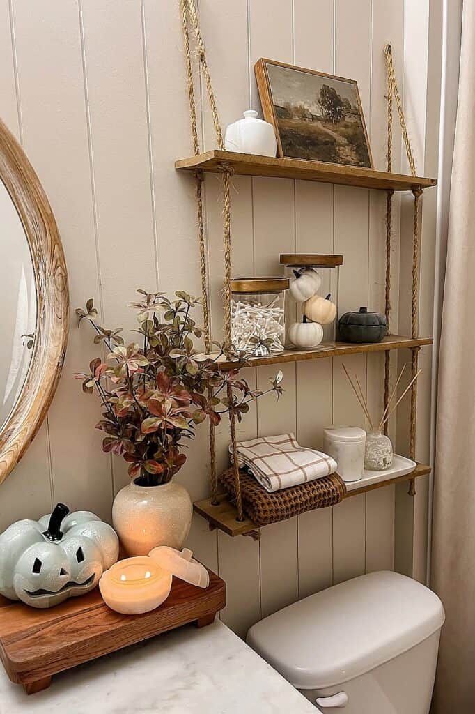 Rustic bathroom shelves with fall-themed decor and pumpkins for autumn ambiance.