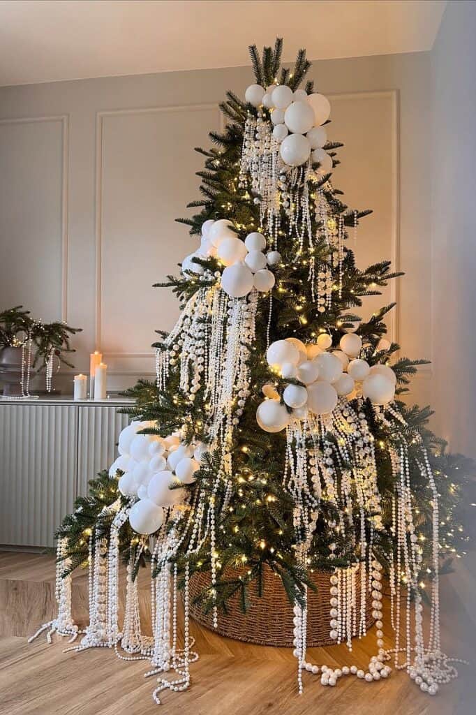 Beautiful white Christmas tree decorated with white ornaments and pearl garlands.