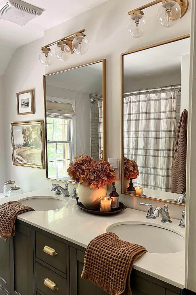 Bright bathroom with double sinks, mirrors, and floral decor for fall.