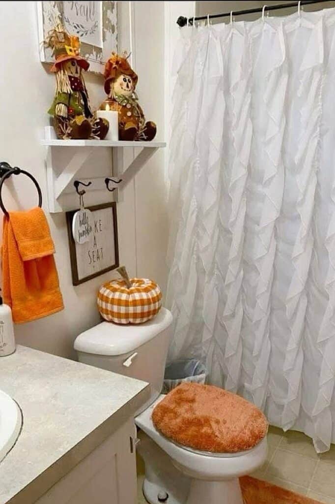 Cozy fall-themed bathroom with pumpkins, plush toilet seat cover, and seasonal decorations.