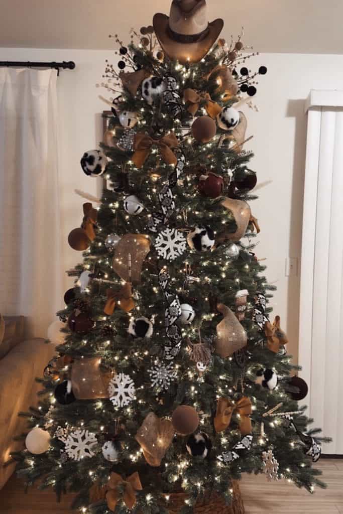 Decorated Christmas tree with gold, black, and white ornaments and lights.
