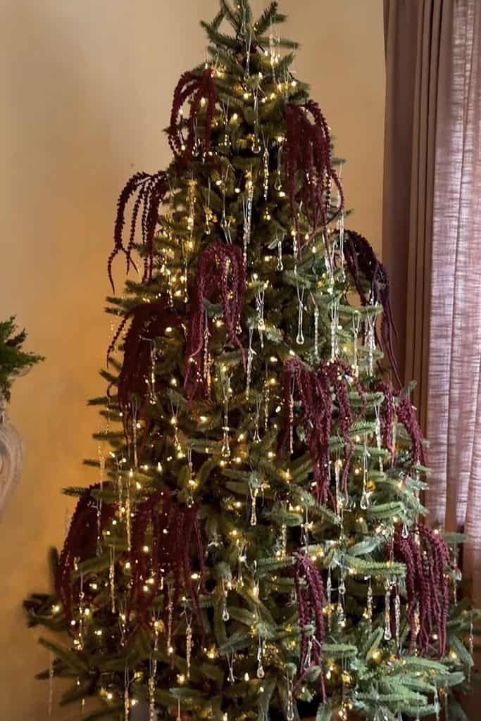Decorated Christmas tree with lights and burgundy ornaments for holiday season.