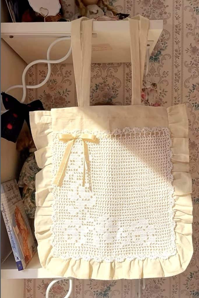 Cream-colored doily bag with ruffled edges and bow detail for home decor.