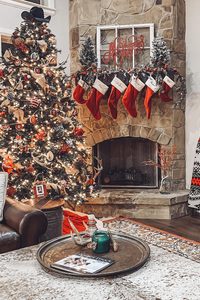 Cozy Christmas fireplace decorated with stockings and a Christmas tree.