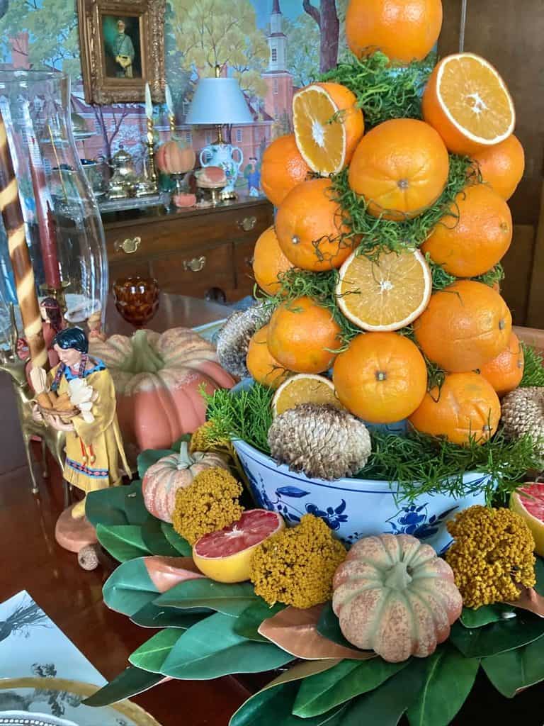 Decorative fall centerpiece with oranges, pumpkins, and greenery for autumn decor.