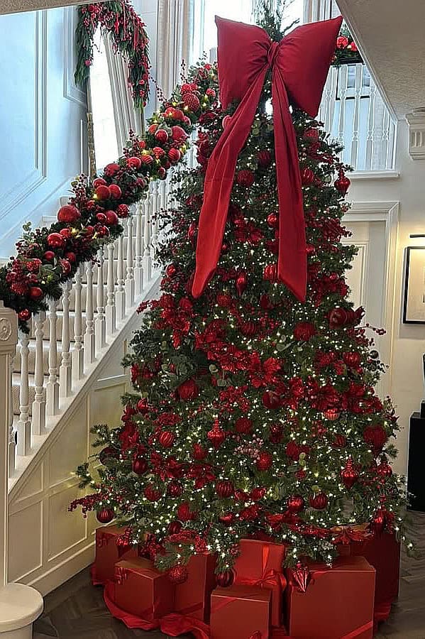 Beautiful Christmas tree with burgundy ornaments and a large red bow.