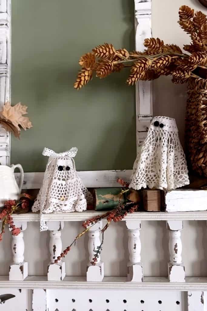 Fall-themed doily crafts with owl and ghost decorations on a white shelf.