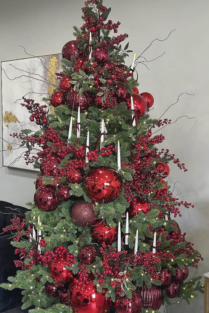 Festive Christmas tree decorated with red ornaments, berries, and candles.