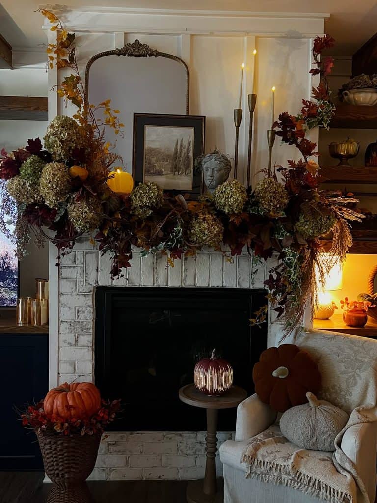 Autumn floral arrangement and pumpkins decorate a cozy fireplace mantel.