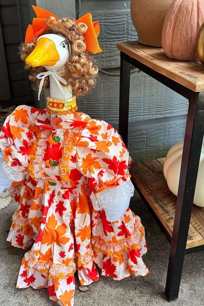Decorative fall-themed goose doll with autumn leaves dress and curly hair.