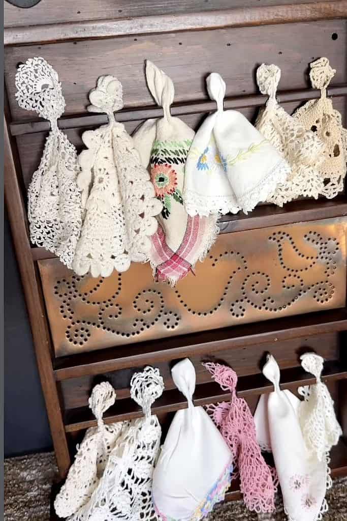 Vintage doilies and cloths hanging on a wooden rack for home decor.