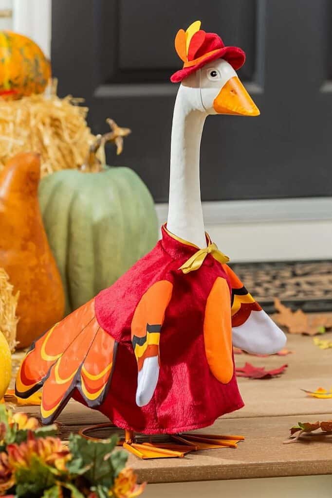 Decorative goose dressed in fall-themed costume with pumpkin and autumn leaves.